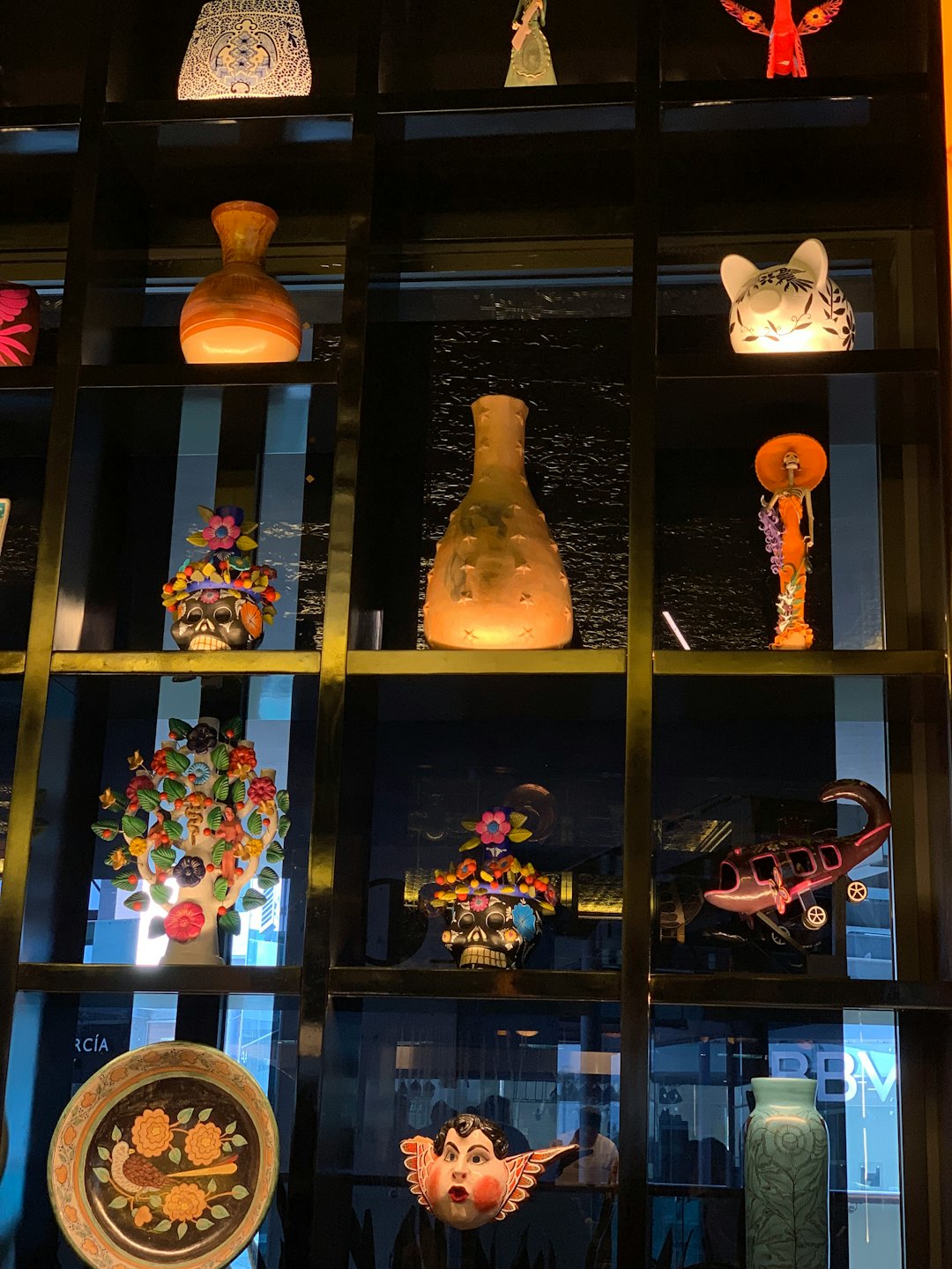 Arte popular mexicano expuesto en una estantería de rejilla.
