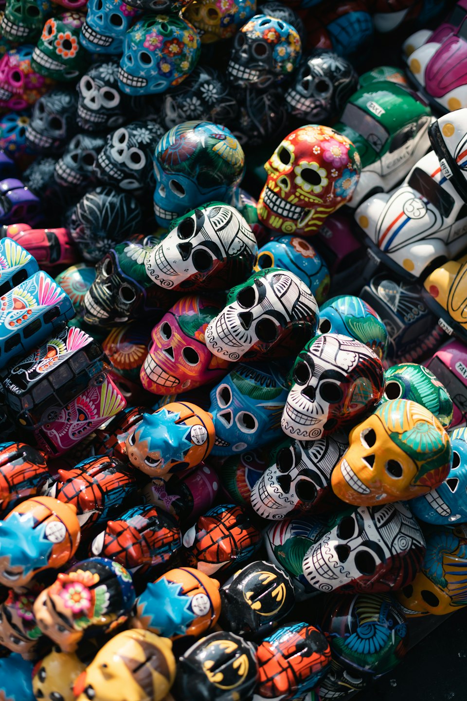 Figurillas artesanales de calaveras de azúcar mexicanas y vehículos pintados con forma de calavera.